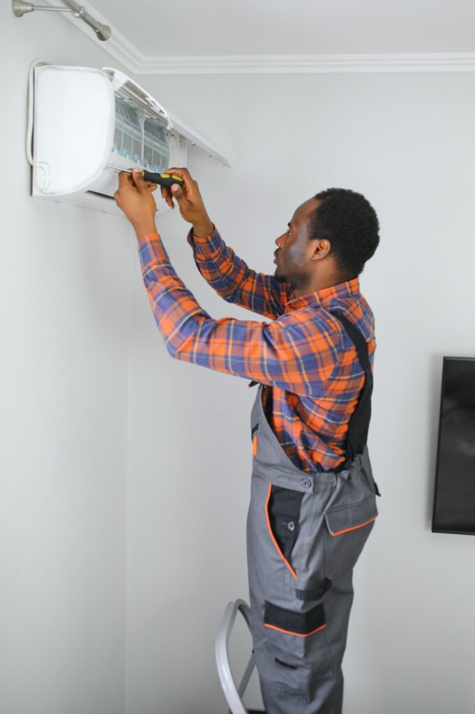 African American electrician repairing air conditioner indoors | Dan's HVAC