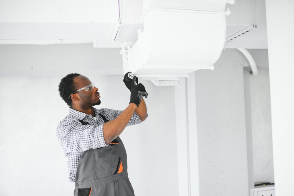 African HVAC Technician Worker Testing Newly Installed Ventilation System.