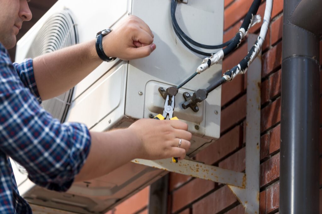 Closeup of male technician repairing outdoor air conditioner unit | Dan's HVAC