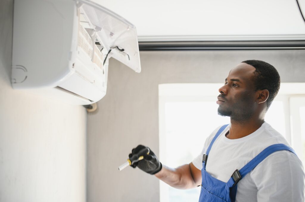 Happy Young African Male Technician Repairing Air Conditioner