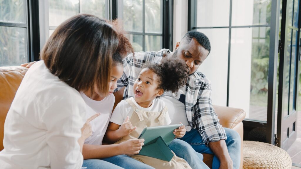 Young African American family and daughter happy using tablet at home.