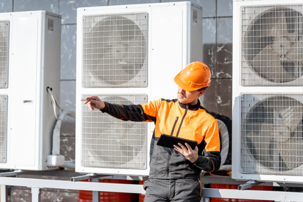 Workman servicing air conditioning or heat pump with digital tablet